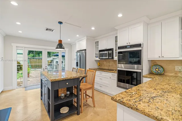 a kitchen with stainless steel appliances granite countertop a stove top oven a sink dishwasher and a refrigerator with the cabinets