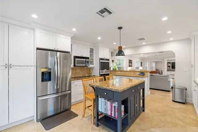 a kitchen with stainless steel appliances granite countertop a refrigerator a sink and a stove