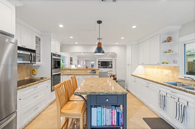 a large kitchen with granite countertop a large counter top appliances and cabinets
