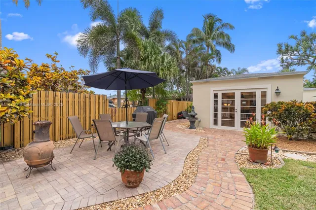 a view of a patio with table and chairs potted plants and palm trees