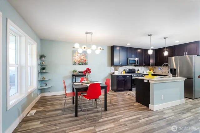 a kitchen with stainless steel appliances kitchen island granite countertop a table chairs and a refrigerator