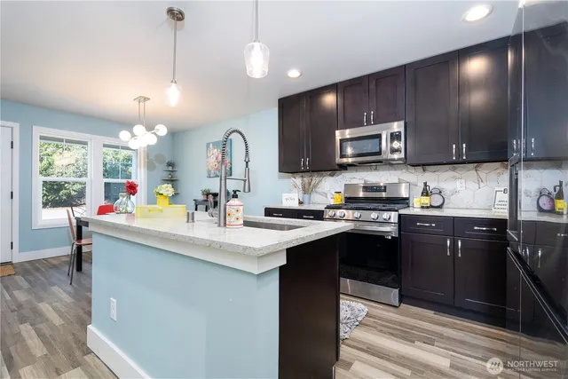 a kitchen with kitchen island stainless steel appliances a sink stove and microwave