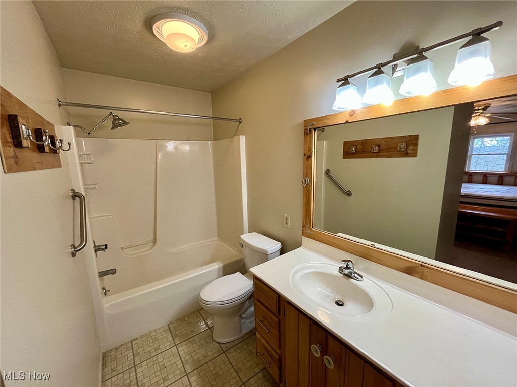 5295 Deer Road Southwest Bowerston, OH 44695 - Photo 17 of 39 Bathroom with shower / washtub combination, toilet, vanity, tile patterned floors, and a textured ceiling