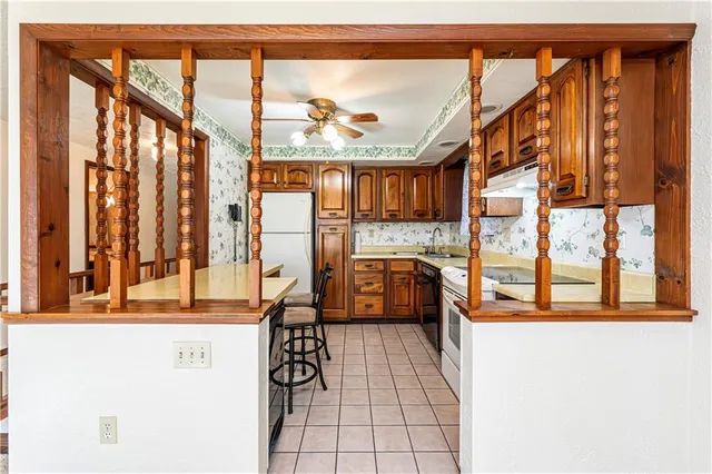 a kitchen with stainless steel appliances granite countertop a refrigerator a sink dishwasher a stove with wooden cabinets and floor