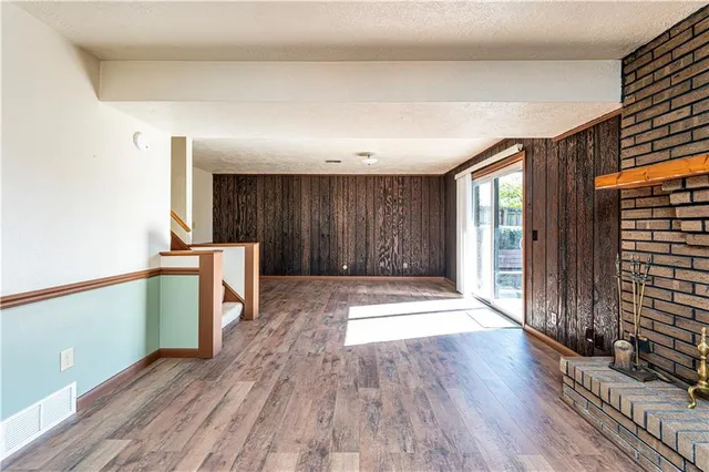 an empty room with wooden floor and a fireplace
