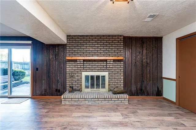 a view of an empty room with wooden floor and a fireplace