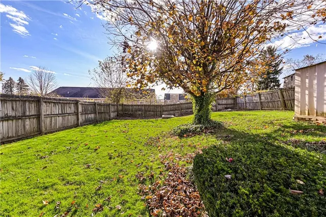 a view of a yard with large trees and a barn in it