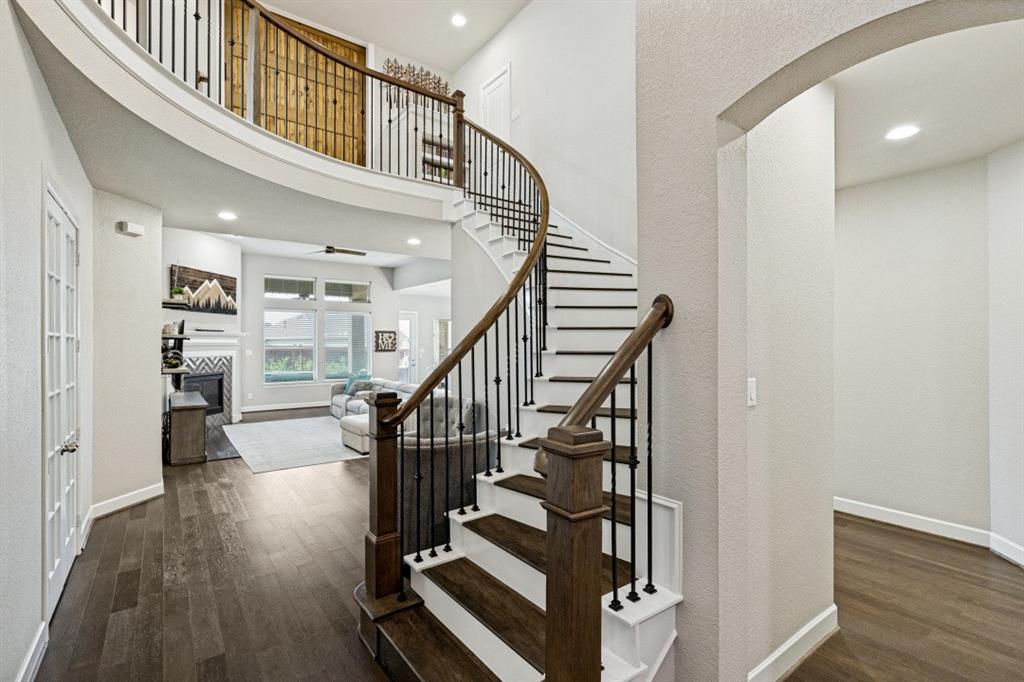 2721 Old Shire Path Road Prosper, TX 75078 - Photo 3 of 40 Curved staircase with wood-finish stairs and rought iron balusters