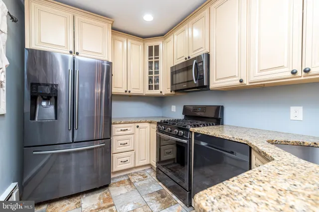 a kitchen with stainless steel appliances granite countertop a refrigerator stove and sink