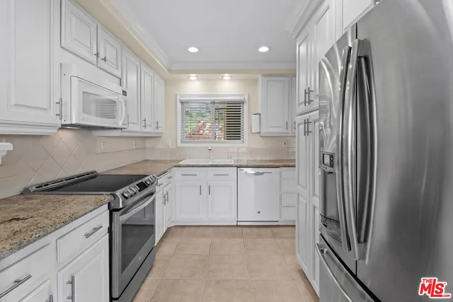 a view of a kitchen with a stove wooden cabinets and entryway
