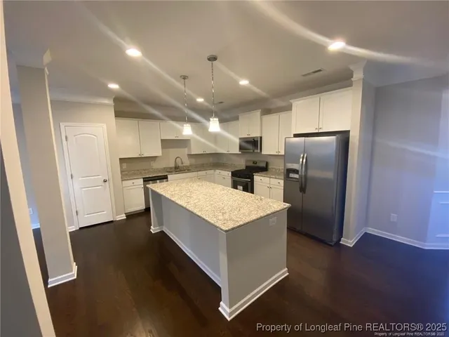 a kitchen with stainless steel appliances kitchen island granite countertop a refrigerator a sink a stove a microwave and island