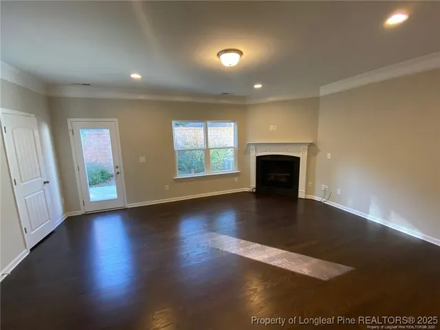 an empty room with wooden floor fireplace and windows