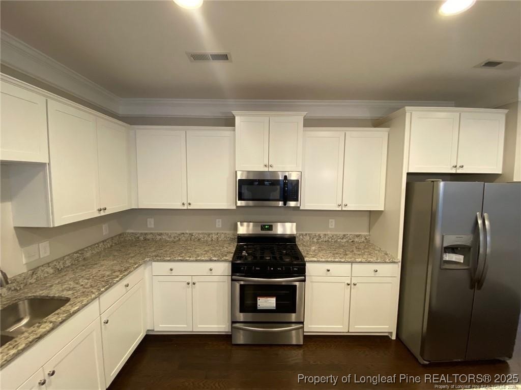 1206 Wingstem Place Raleigh, NC 27607 - Photo 7 of 17 a kitchen with stainless steel appliances granite countertop a stove a refrigerator and a cabinets