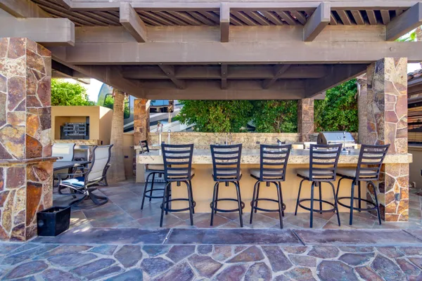a view of a patio with table and chairs a barbeque with wooden floor and roof