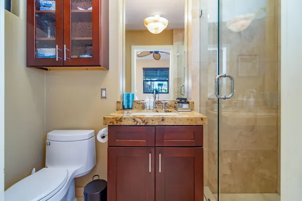 a bathroom with a granite countertop toilet sink and mirror