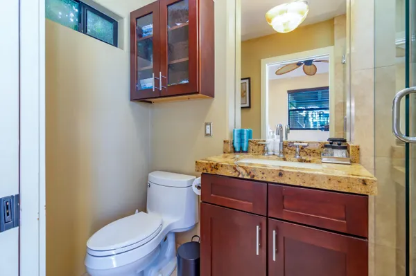 a bathroom with a granite countertop toilet sink and mirror