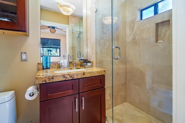 a bathroom with a granite countertop sink a mirror and shower
