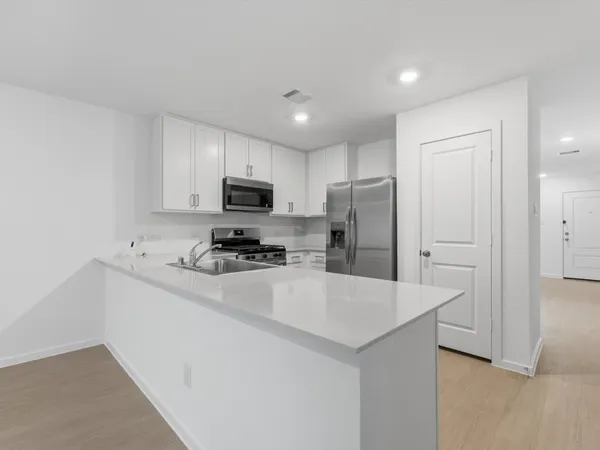 a kitchen with a refrigerator a stove top oven a sink and cabinets
