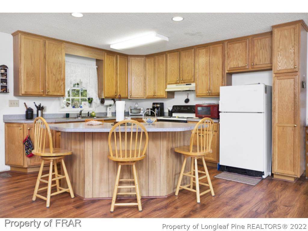 5253 Lobelia Road Vass, NC 28394 - Photo 12 of 28 a kitchen with stainless steel appliances a stove a refrigerator a sink a dining table and chairs