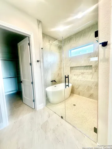 a bathroom with a tub and a glass door shower