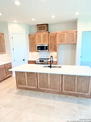 a kitchen with cabinets a sink and a stove top oven with wooden floor