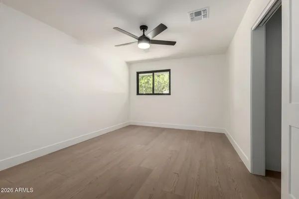 an empty room with wooden floor ceiling fan and window