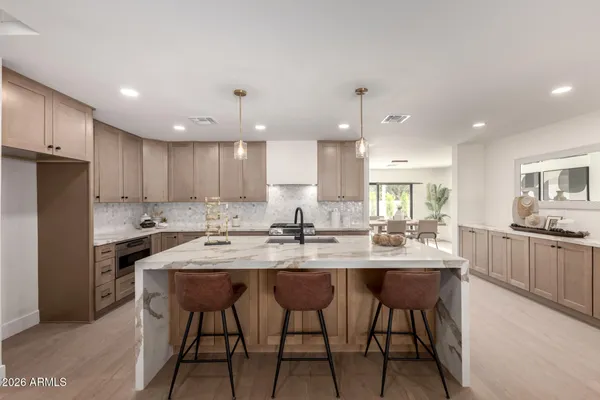 a kitchen with stainless steel appliances kitchen island granite countertop a dining table chairs stove refrigerator and cabinets