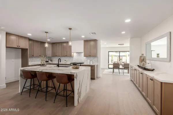a kitchen with kitchen island a sink a stove a dining table and chairs