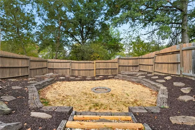 a view of a backyard with wooden fence and large trees