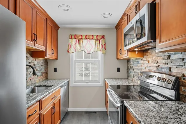 a kitchen with stainless steel appliances granite countertop a stove a sink and a microwave