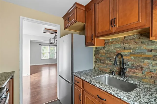 a kitchen with stainless steel appliances granite countertop a sink and a refrigerator