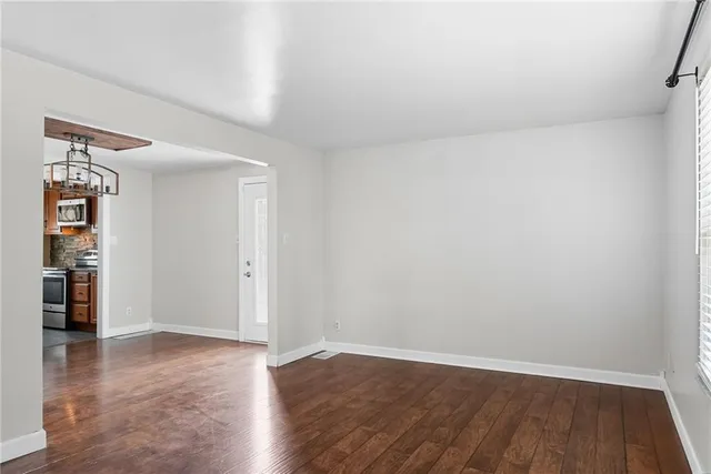 a view of an empty room with wooden floor and closet