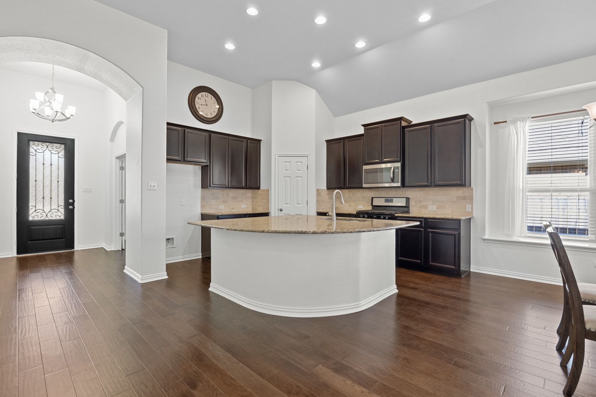 228 Sangiovese Leander, TX 78641 - Photo 4 of 32 a large kitchen with stainless steel appliances granite countertop a stove a sink dishwasher and a microwave with wooden floor