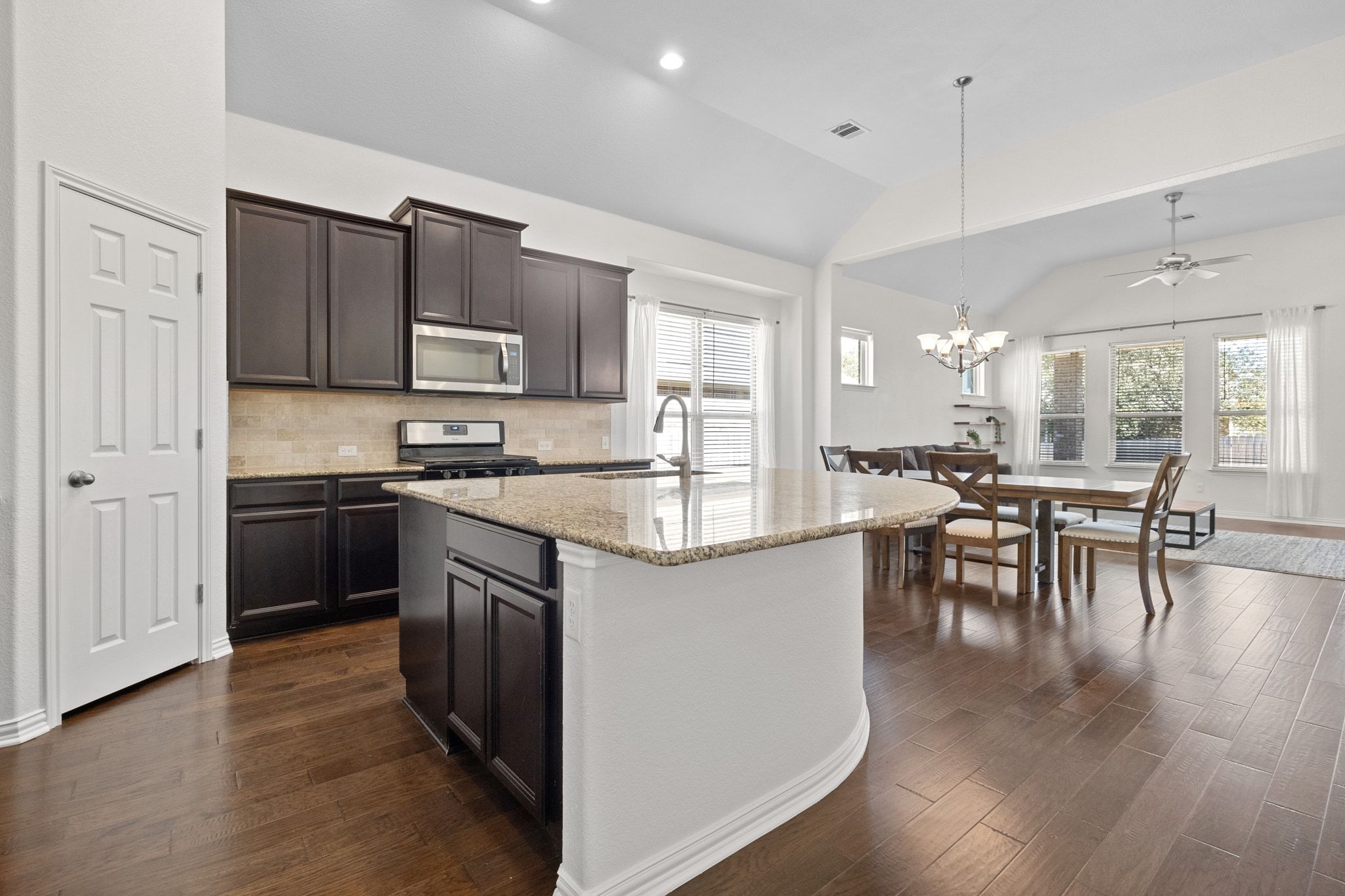 228 Sangiovese Leander, TX 78641 - Photo 8 of 32 a kitchen with stainless steel appliances granite countertop a stove top oven a sink a dining table and chairs with wooden floor