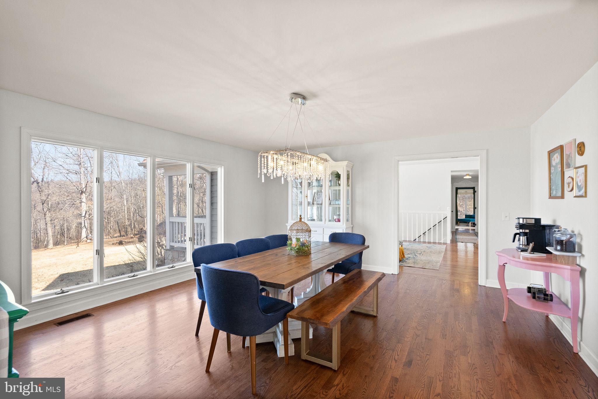 8089 Moormont Road Rapidan, VA 22733 - Photo 16 of 88 a dining room with wooden floor a chandelier a glass table and chairs