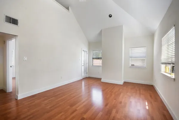 an empty room with wooden floor and windows