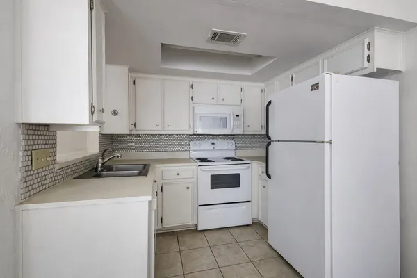 a kitchen with a refrigerator a stove a sink and white cabinets