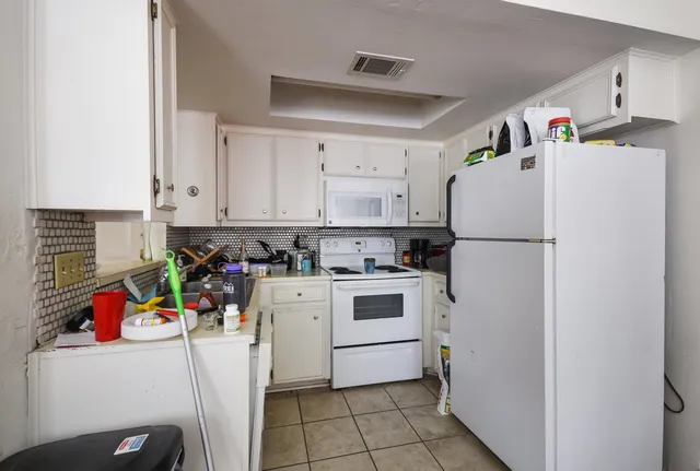 a kitchen with a refrigerator and white cabinets