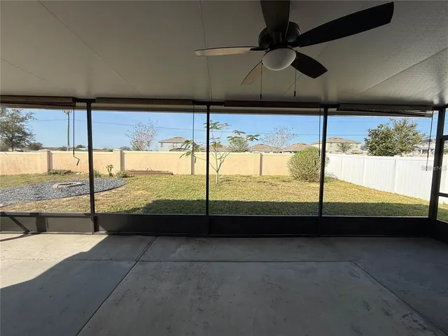 a view of an empty room with a floor to ceiling window and a ceiling fan