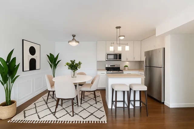 a kitchen with stainless steel appliances a dining table chairs refrigerator and sink