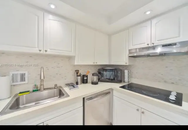 a kitchen with stainless steel appliances granite countertop a sink a stove and white cabinets