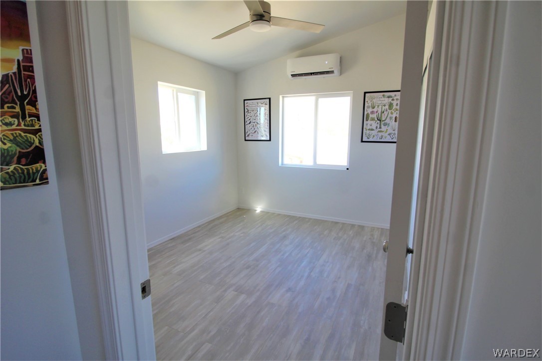11722 Suzette Road Yucca, AZ 86438 - Photo 18 of 29 a view of an empty room with a window and wooden floor