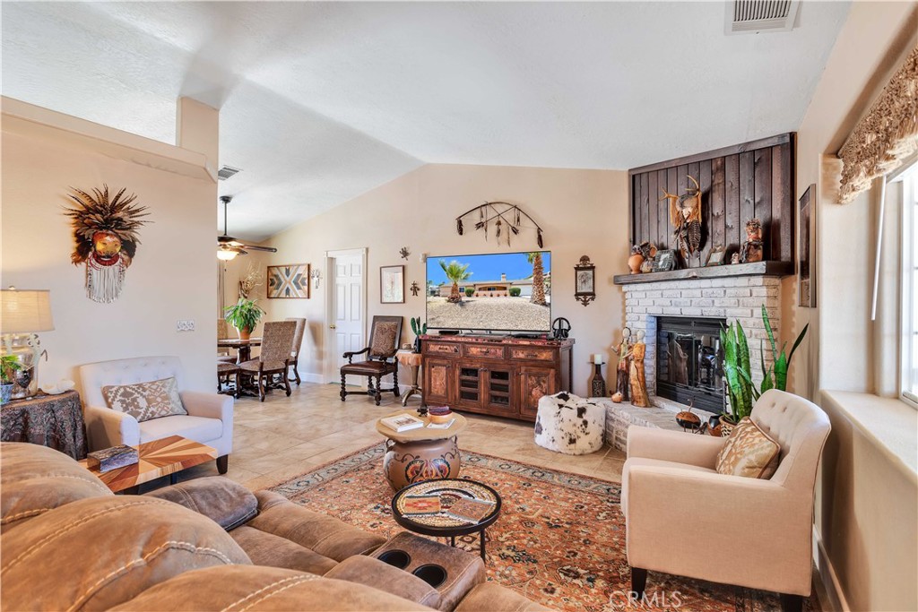 57490 Redondo Street Yucca Valley, CA 92284 - Photo 12 of 60 a living room with furniture a fireplace a window and a flat screen tv