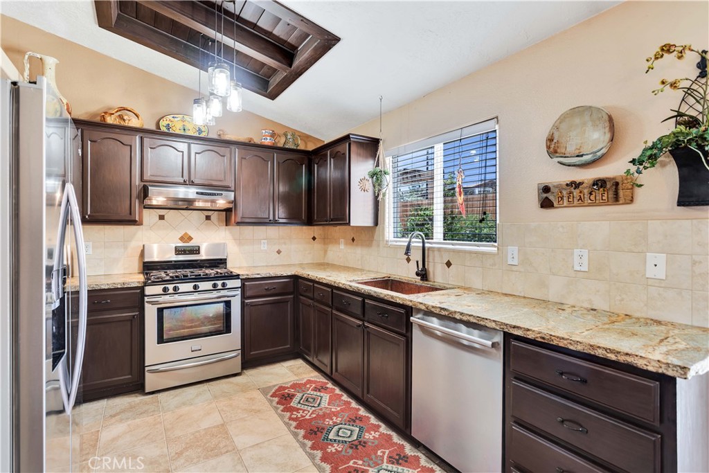 57490 Redondo Street Yucca Valley, CA 92284 - Photo 14 of 60 a kitchen with stainless steel appliances granite countertop a sink a stove a refrigerator cabinets and a window