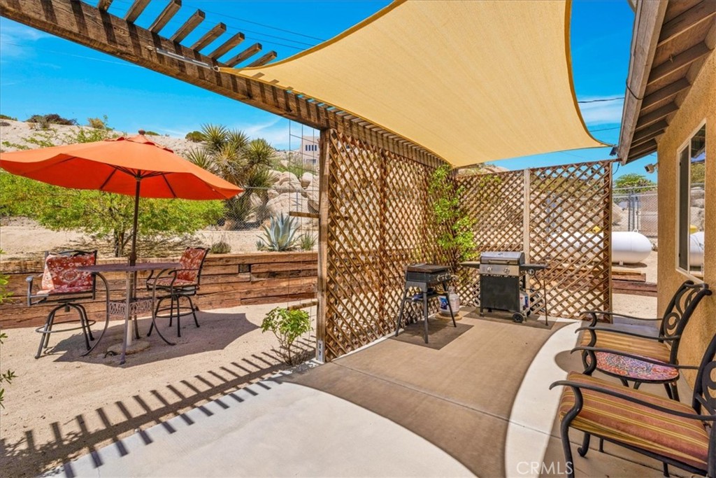 57490 Redondo Street Yucca Valley, CA 92284 - Photo 34 of 60 a view of a patio with a table chairs and a umbrella