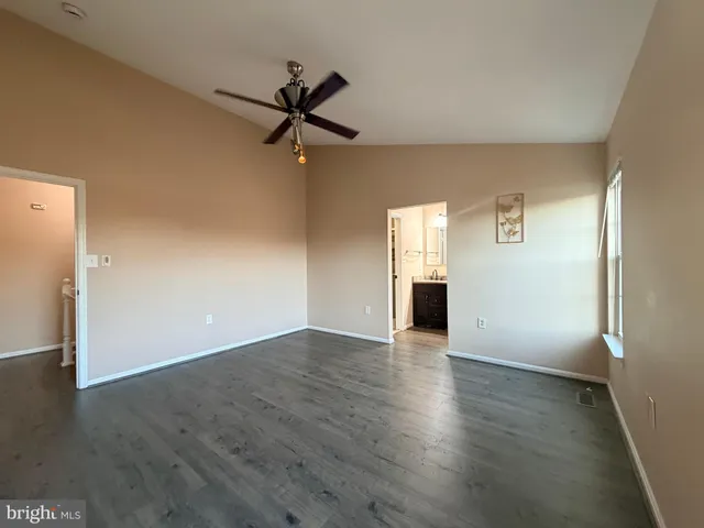 an empty room with wooden floor closet and windows