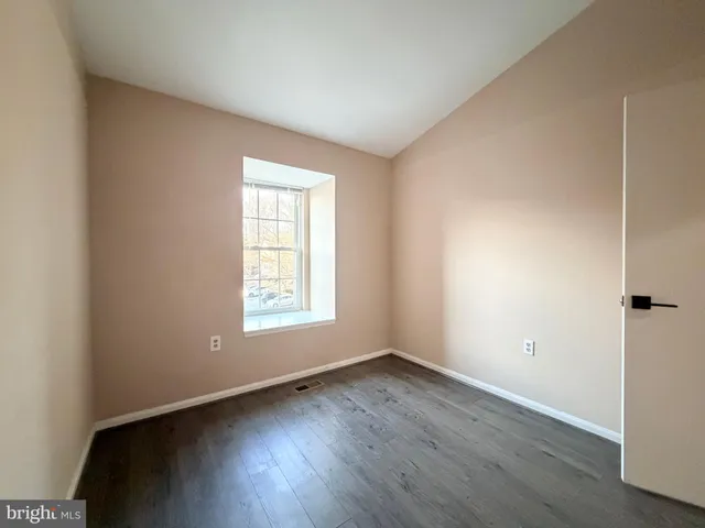 an empty room with wooden floor and window