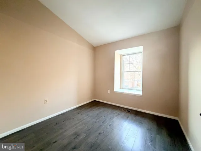 an empty room with wooden floor and window