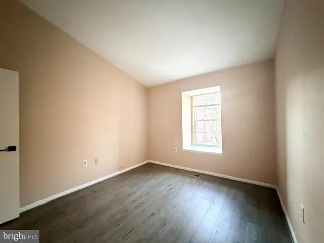 an empty room with wooden floor and window