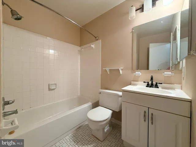 a bathroom with a toilet sink vanity granite tub and shower